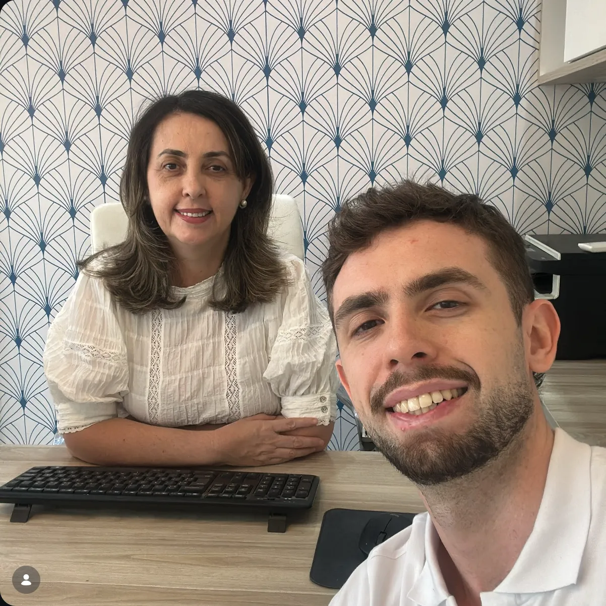 Gabriel Bauer faz uma selfie com a Vânia Beletate sentada à mesa do consultório